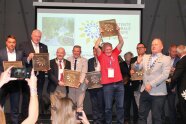 Gruppe von Männern stehen auf einer Bühne mit Metallplaketten in der Hand